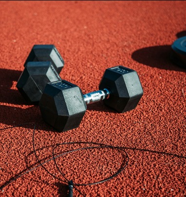 Dumbbells and a skipping rope on a red gym floor